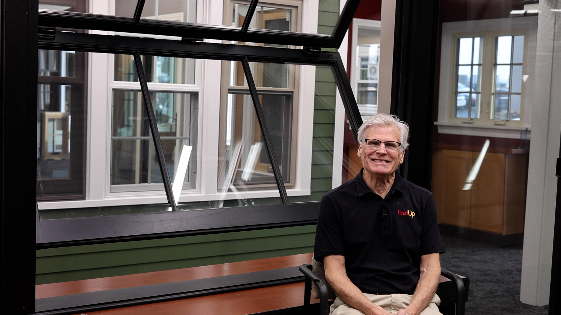 Tim Forster smiling while sitting in front of a large FoldUp window